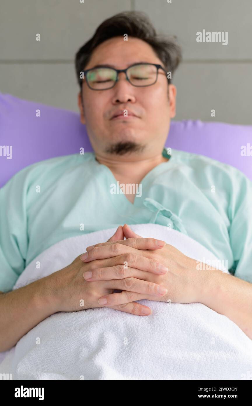 Young man having a restful sleep in a hospital bed Stock Photo