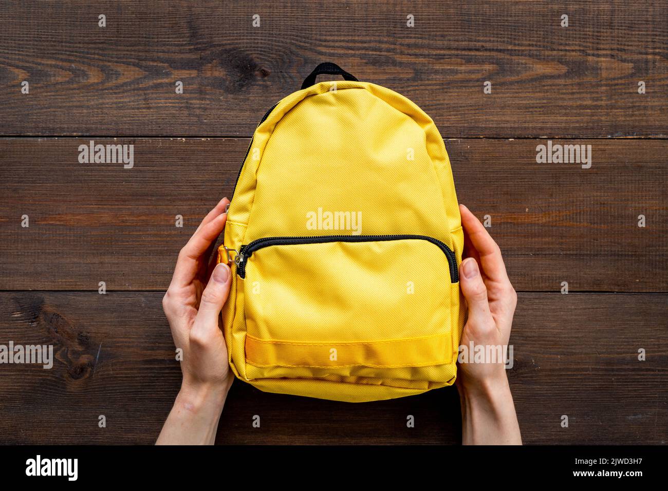 Classic yellow school backpack top view. Educational objects background