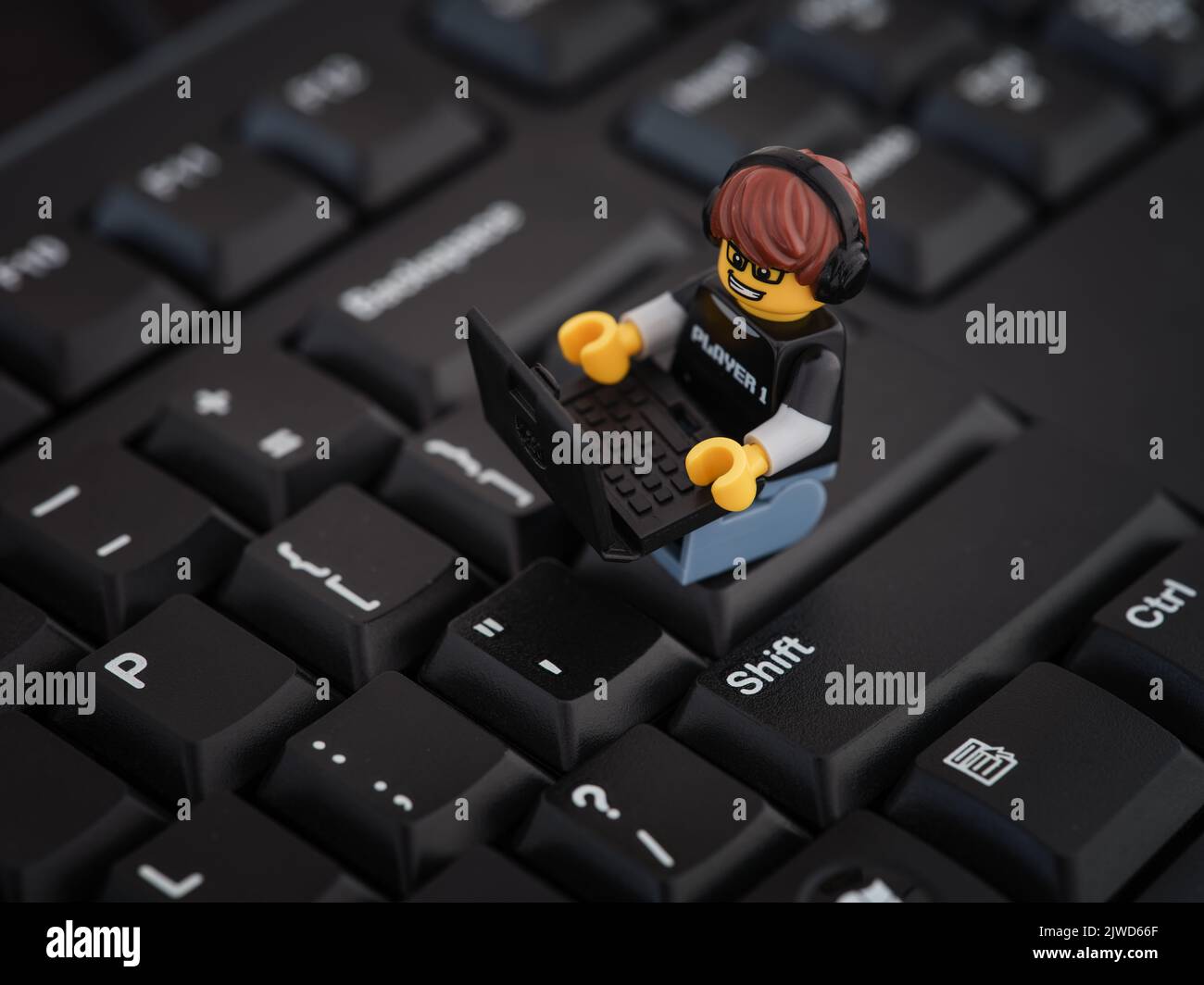 Tambov, Russian Federation - August 25, 2022 A Lego Video Game Guy minifigure sitting on a computer keyboard and playing on a laptop. Stock Photo