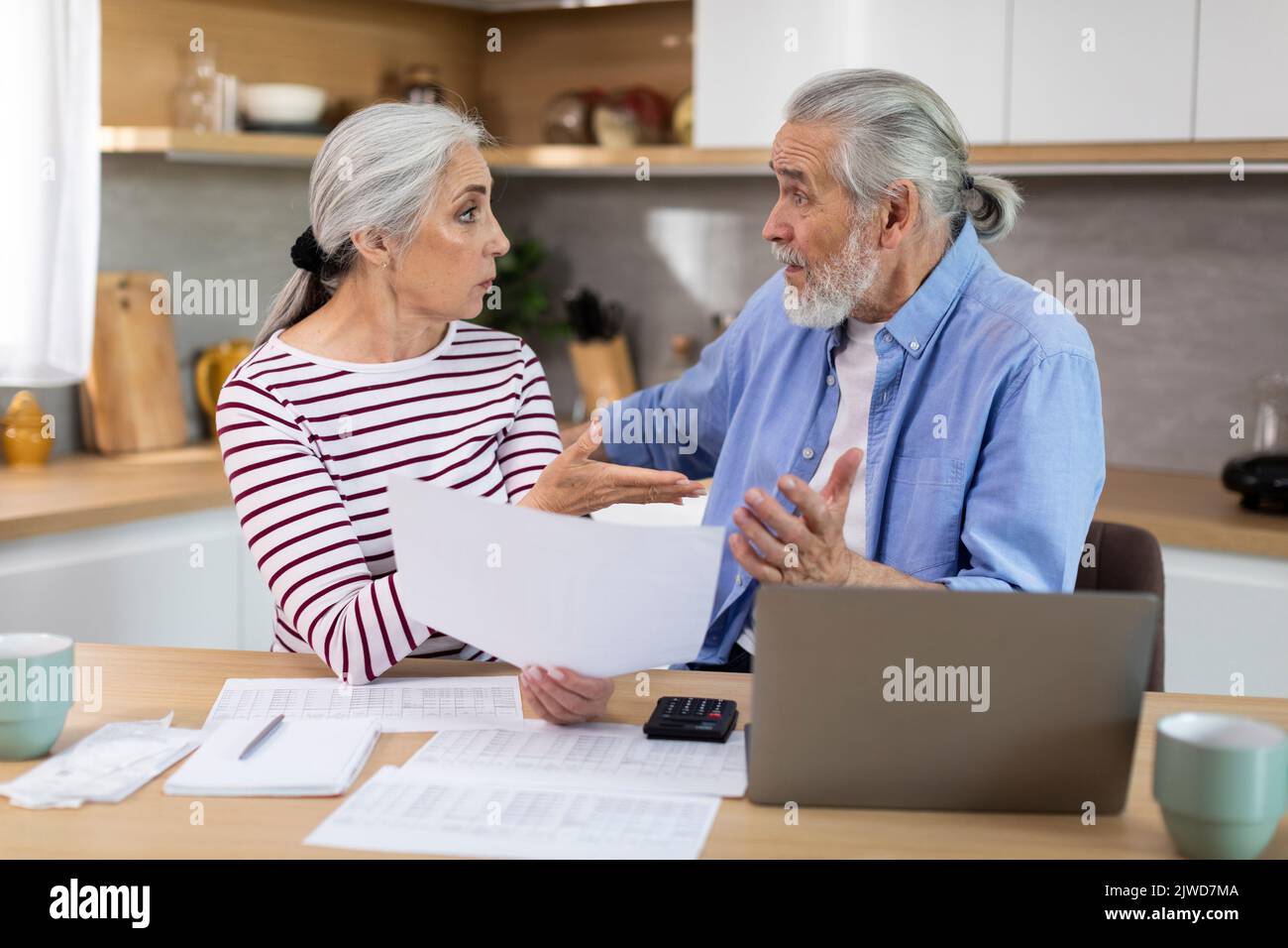 Worried Elderly Spouses Checking Financial Documents In Kitchen At Home Stock Photo