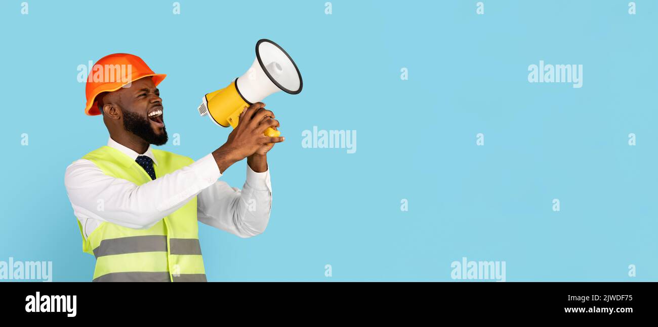 Emotional Black Builder Man Making Announcement With Loudspeaker Over Blue Background Stock Photo
