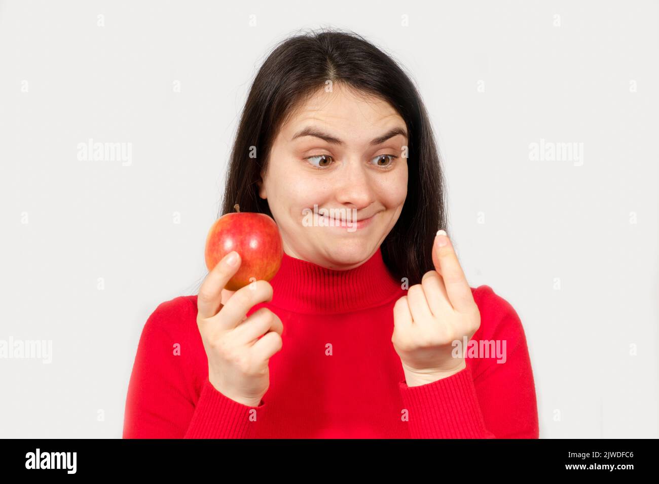 A woman in red holds an apple and a pill in her hands. Vitamins in natural form and in synthetic, dietary supplements Stock Photo