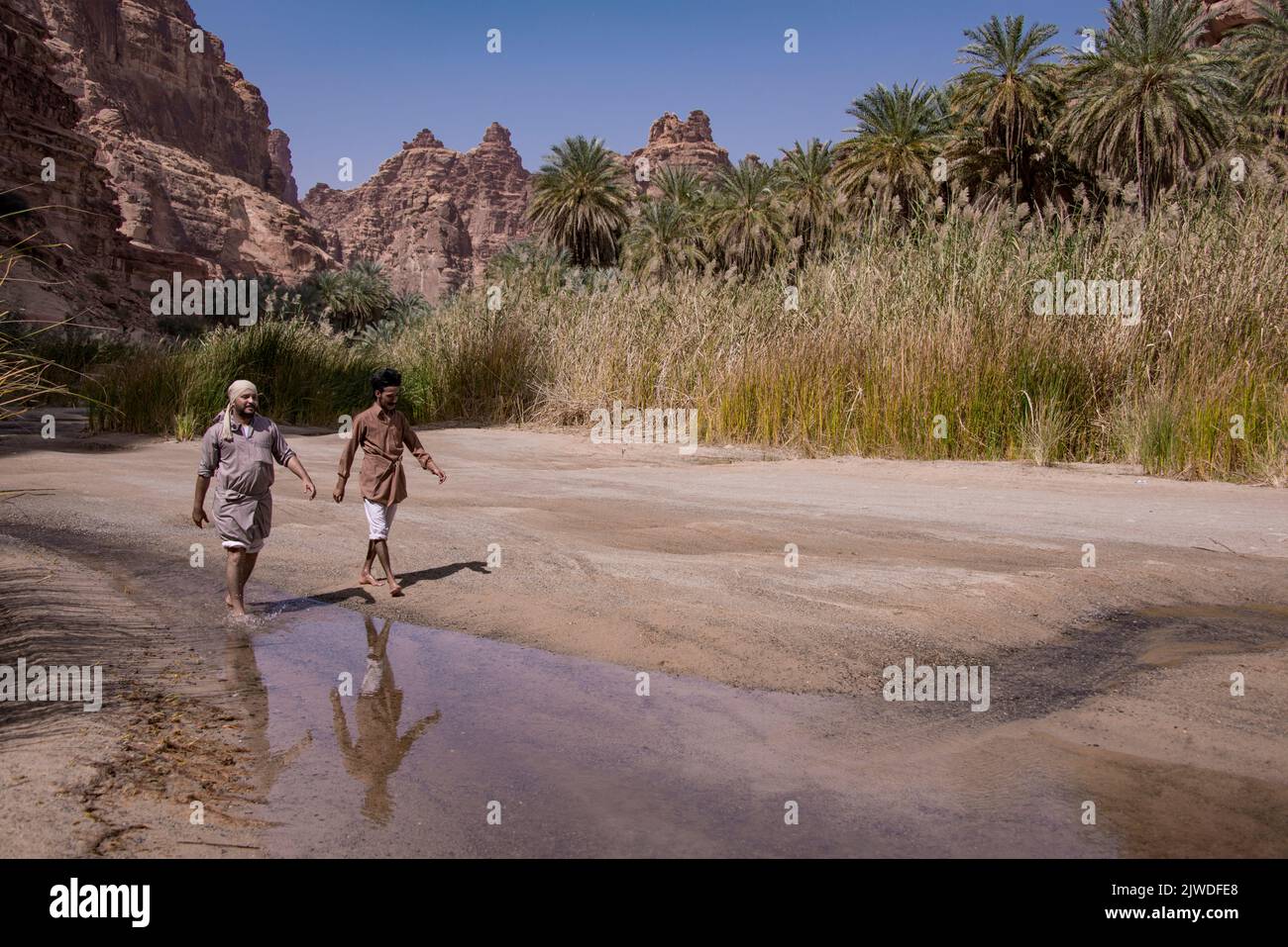 Two Arab men walking through   Wadi Disah Tabuk Province Saudi Arabia Stock Photo