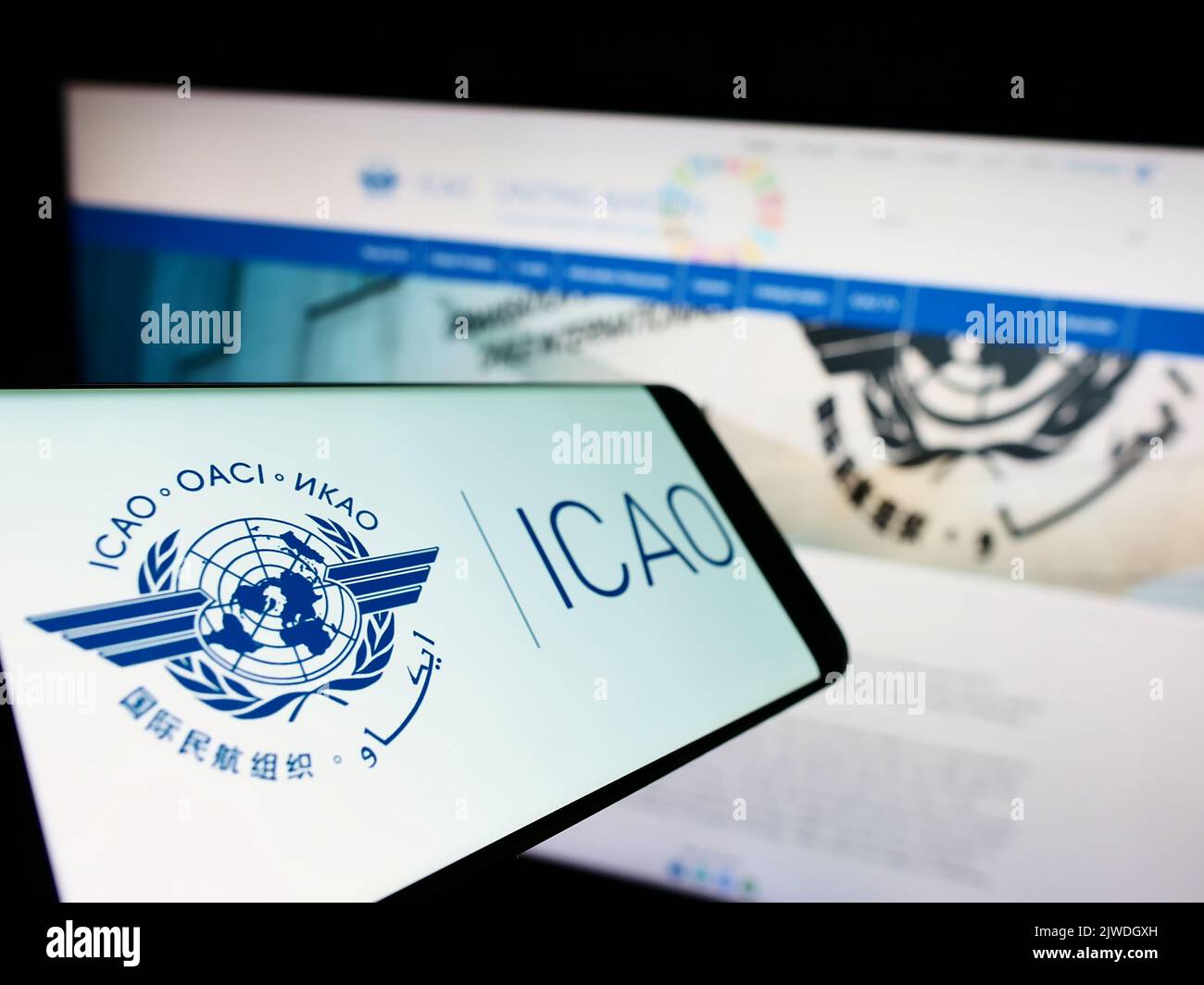 Mobile phone with logo of International Civil Aviation Organization (ICAO) on screen in front of website. Focus on center-left of phone display. Stock Photo