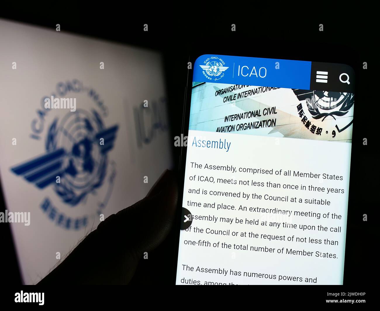 Person holding cellphone with website of International Civil Aviation Organization (ICAO) on screen with logo. Focus on center of phone display. Stock Photo