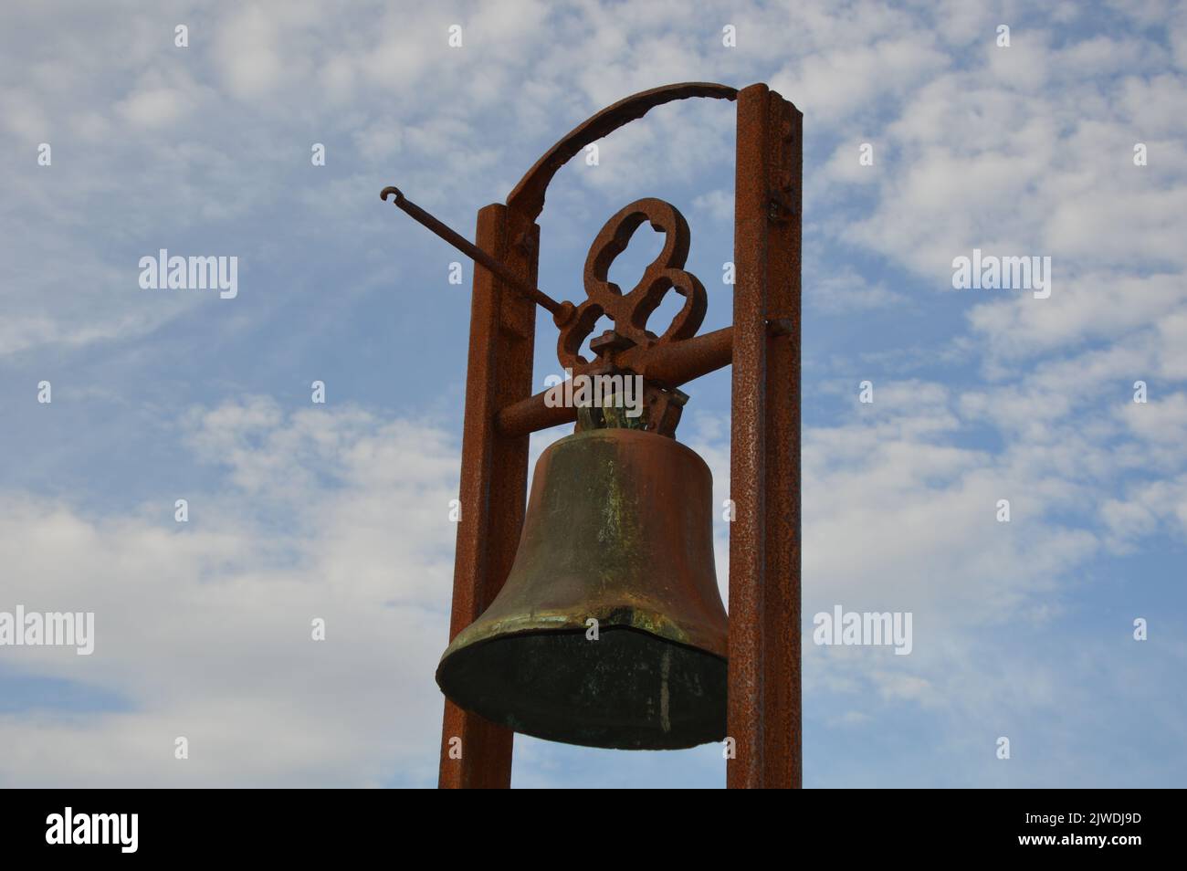 A closeup of an old rusty bell against a cloudy blue sky Stock Photo ...