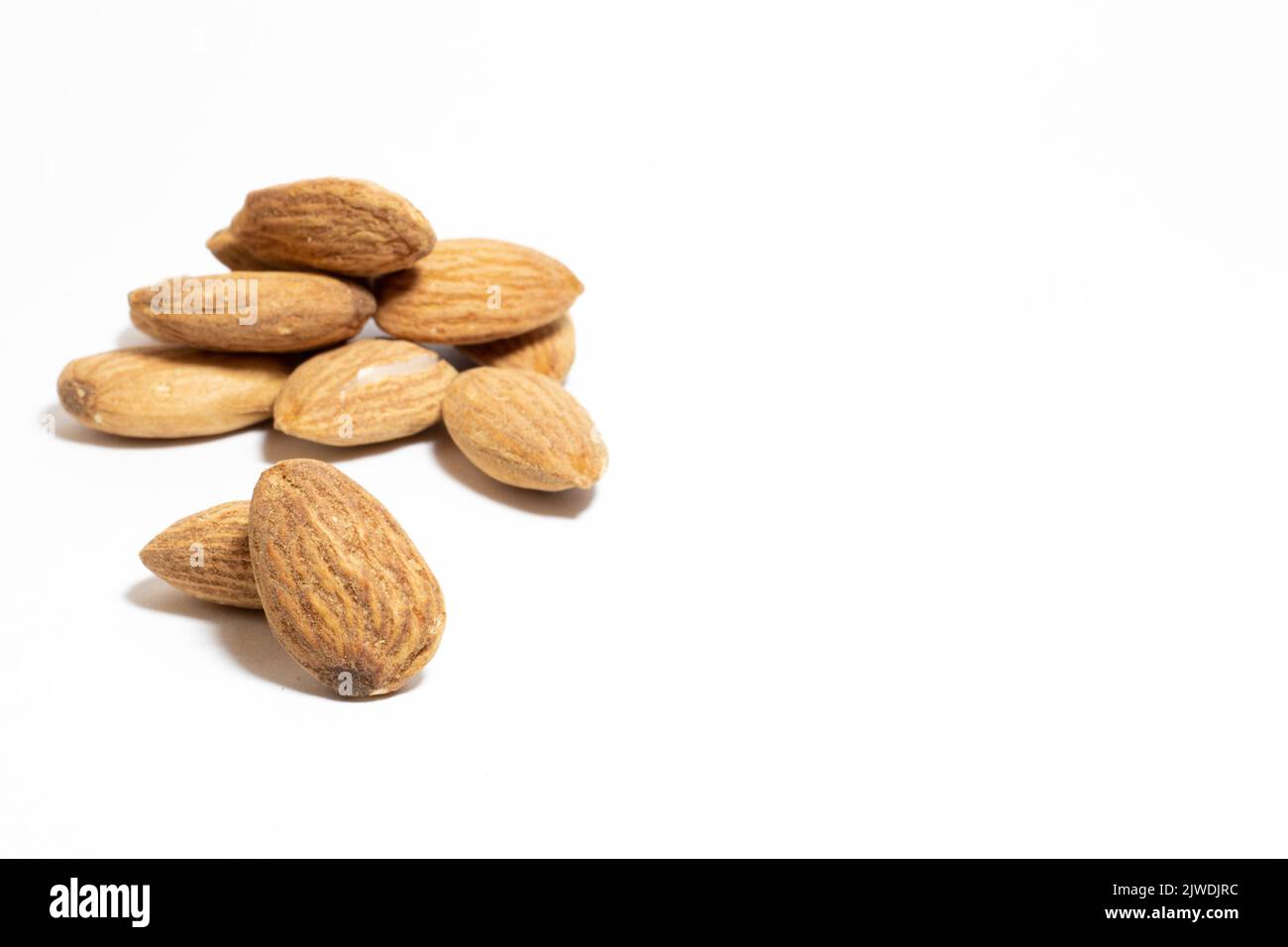 Roasted almonds isolated on a white background. Selective focus peeled  almonds. Healthy nuts idea concept. Copy space, space for text. No people. Stock Photo