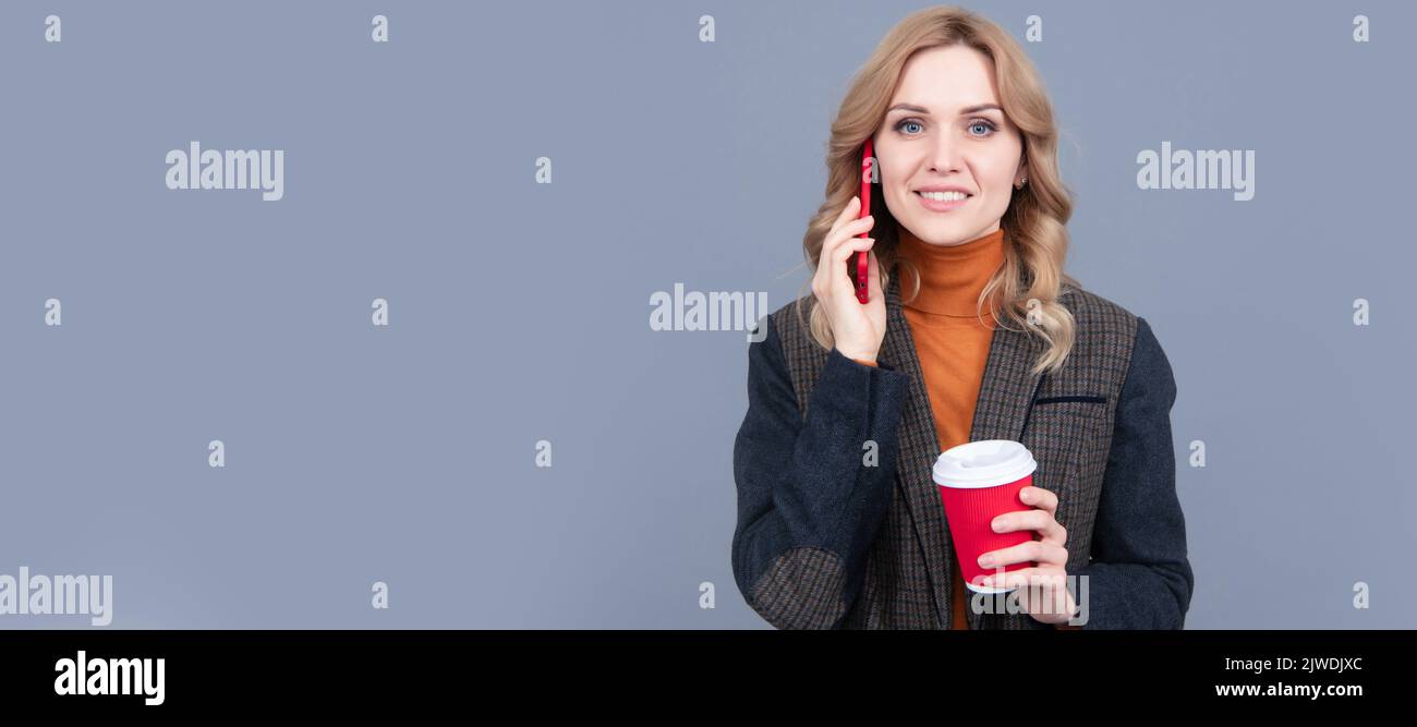 Happy woman talk on mobile phone drinking morning coffee grey background, talker. Woman portrait, isolated header banner with copy space. Stock Photo