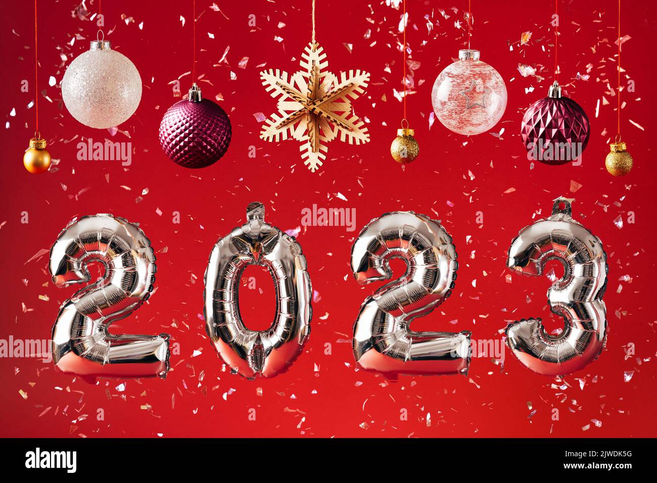 2023 New Year Celebration - silber balloon numbers and decorations on bright red glitter background Stock Photo