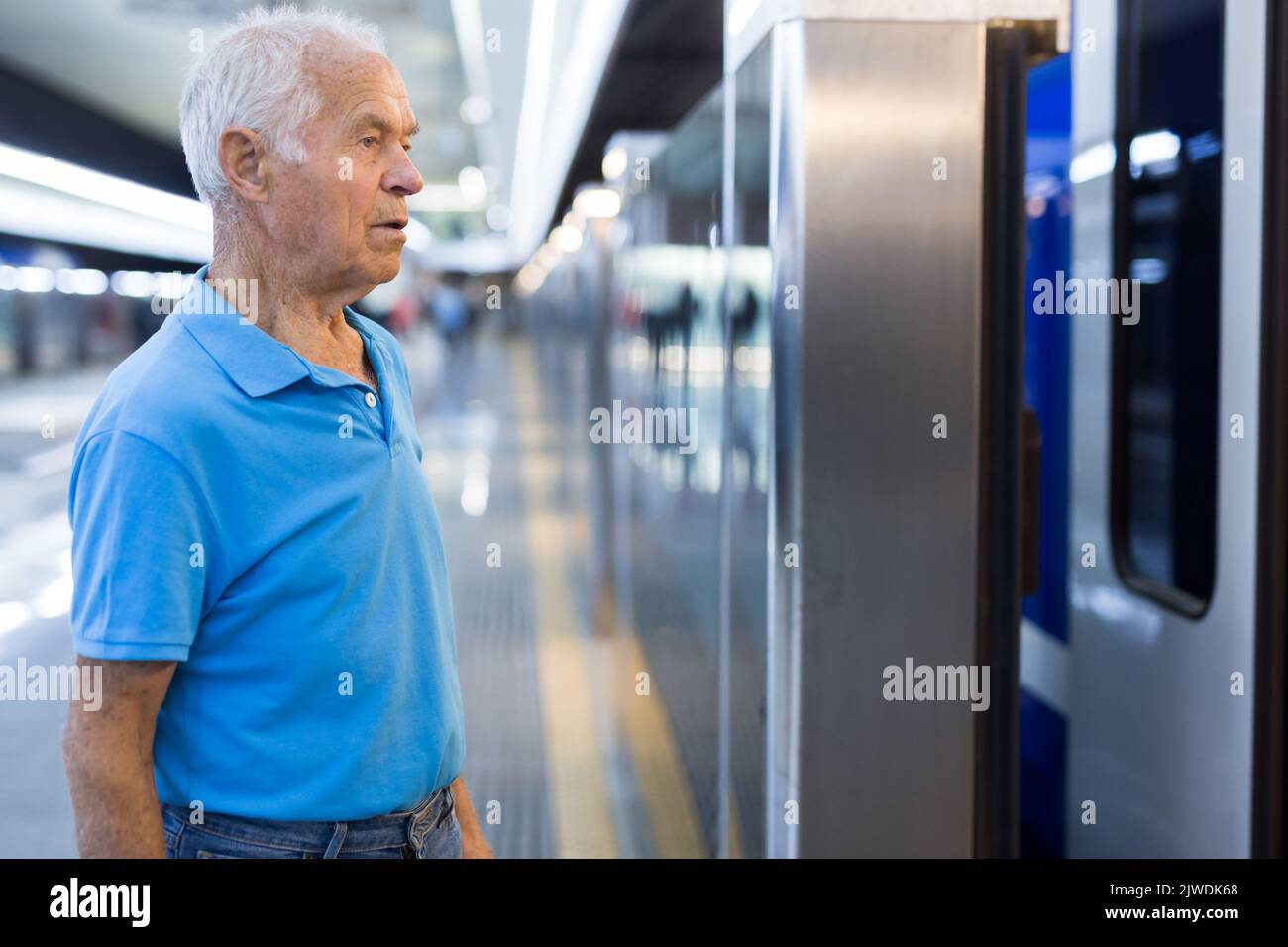 Elderly man getting on modern subway car. Concept of daily city trips Stock Photo