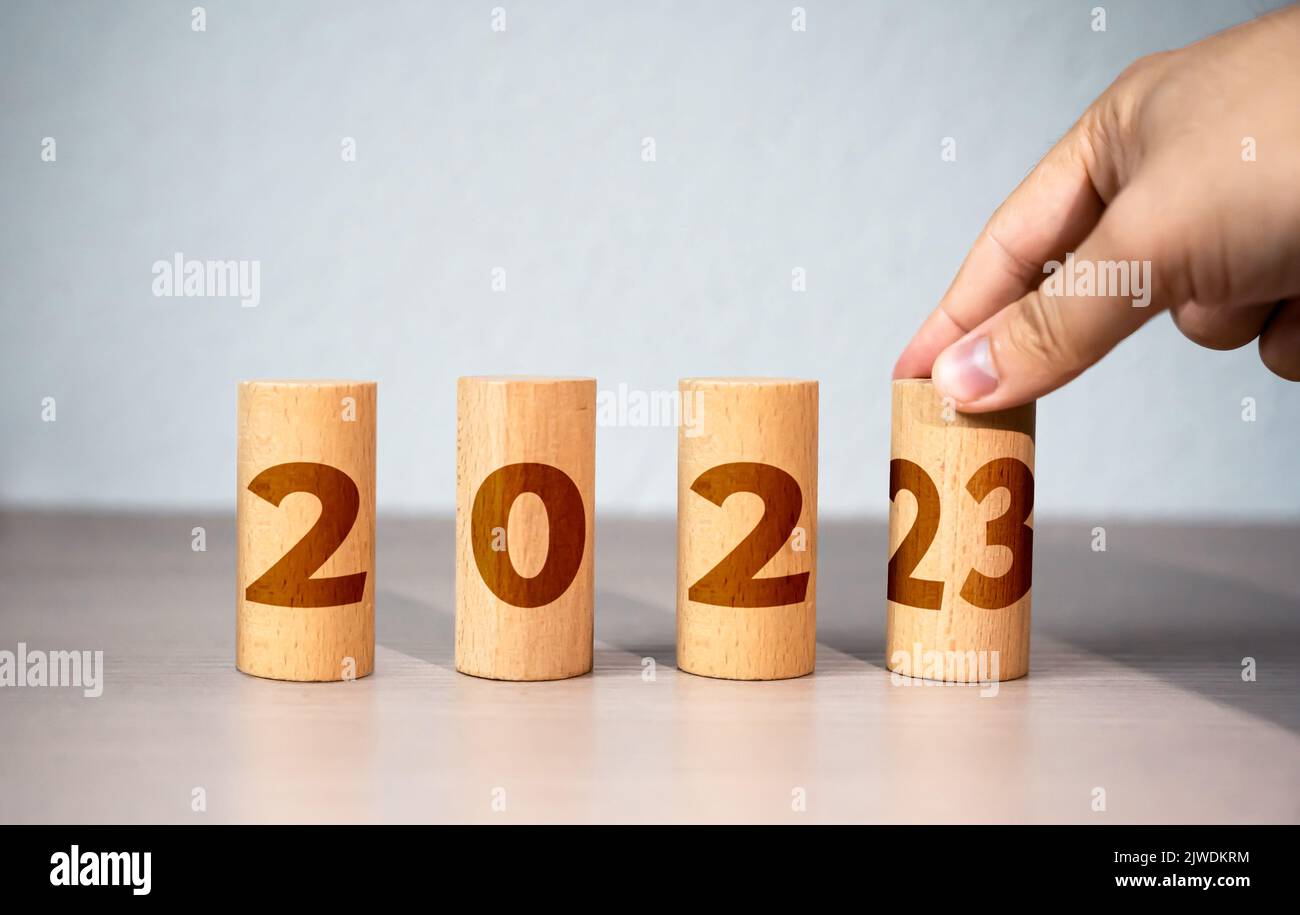 The hand changes the year from 2022 to 2023. New Year and Christmas holidays. Trends and changes, new challenges . Plans and goals. Trends and ideas. Stock Photo