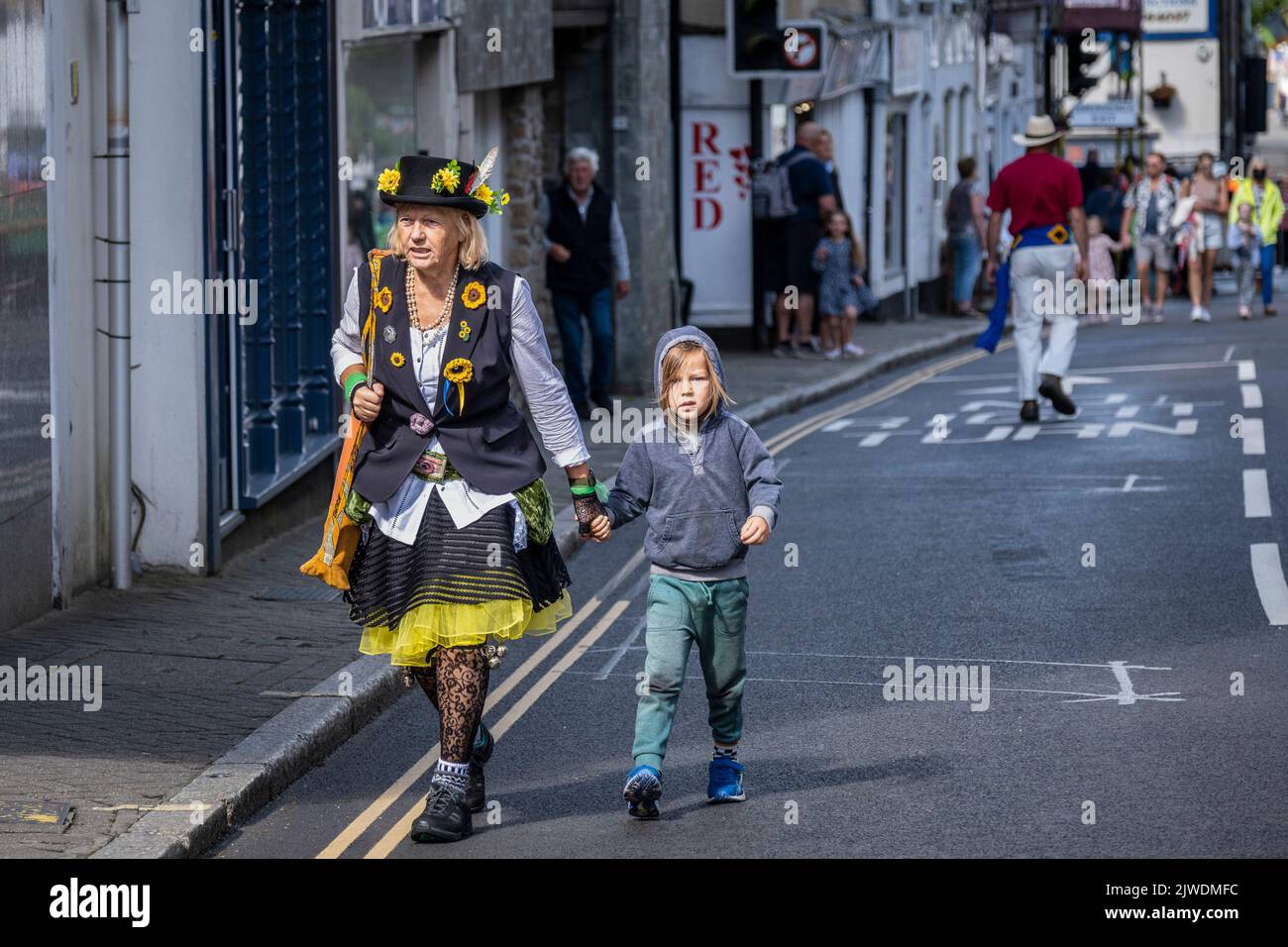 A member of the the Pensans Morris walking holding hands with a young child on Mazey Day part of the Golowan Festival in Penzance in Cornwall in the U Stock Photo