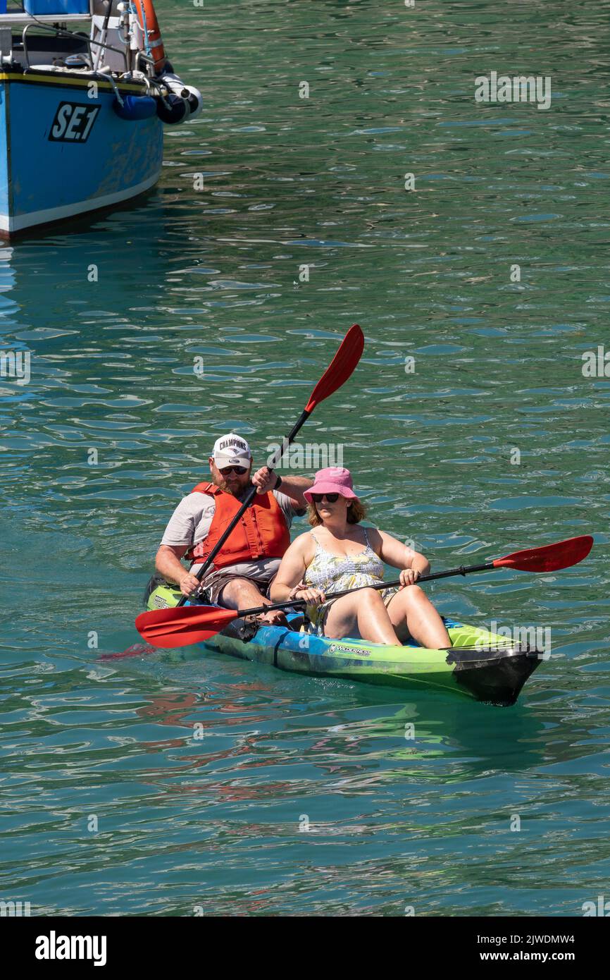 Holidaymakers Visitors Couple Sit on Kayak Newqay Harbour In Cornwall in England in the UK. Stock Photo