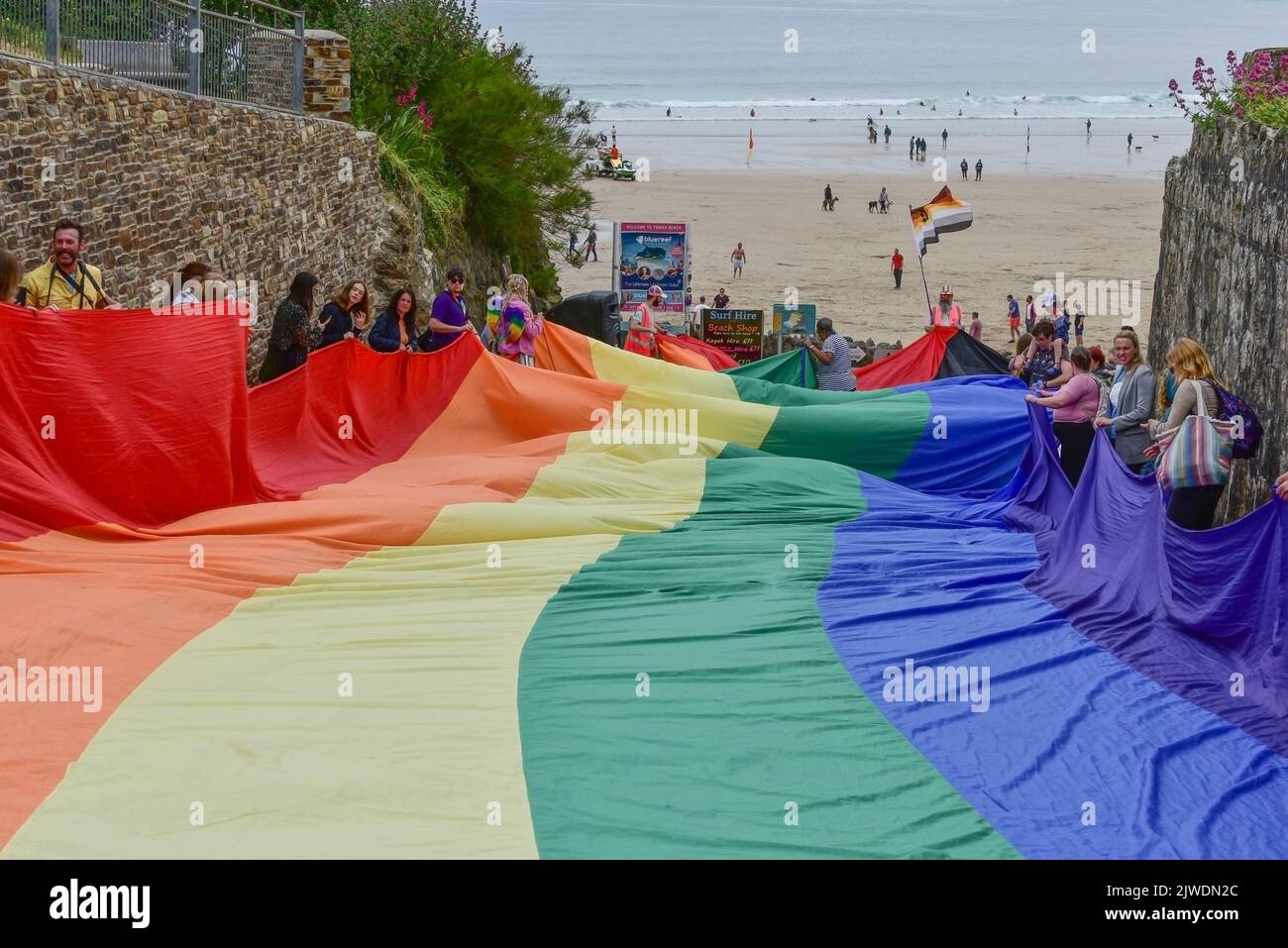 The huge vibrant colourful Cornwall Prides Pride flag banner held by participants in the parade at Towan Beach in Newquay in Cornwall in the UK. Stock Photo