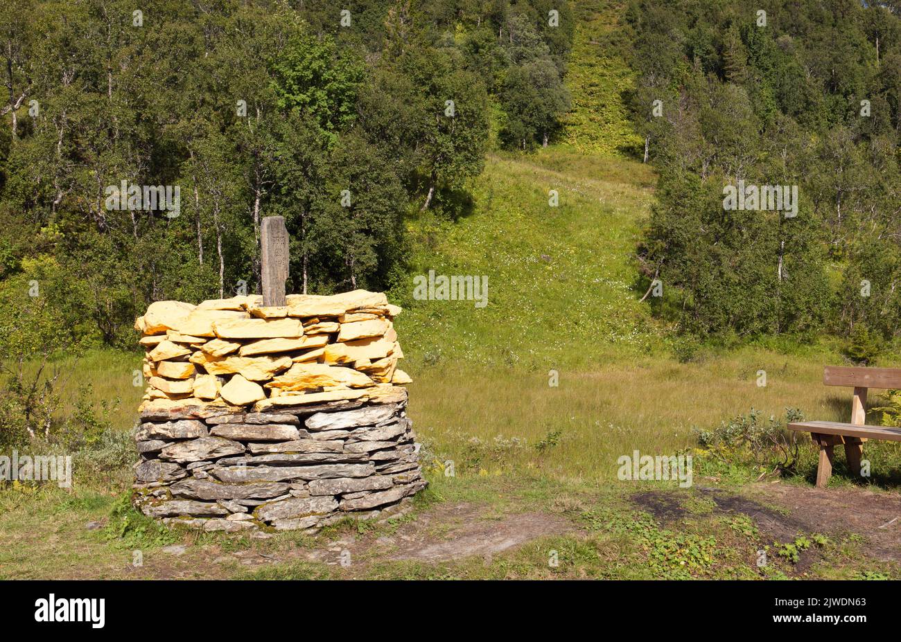 A yellow country chain between Sweden and Norway. Border, hill and wood in the background. Bright sunshine. Stock Photo