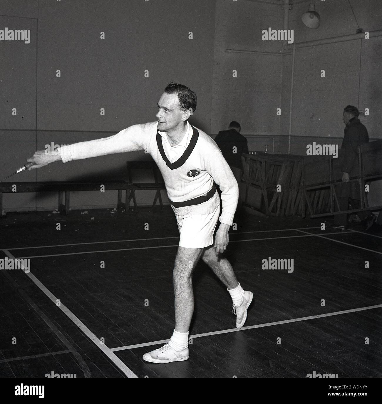 1965, historical, Scottish male badminton player on a court, stretching