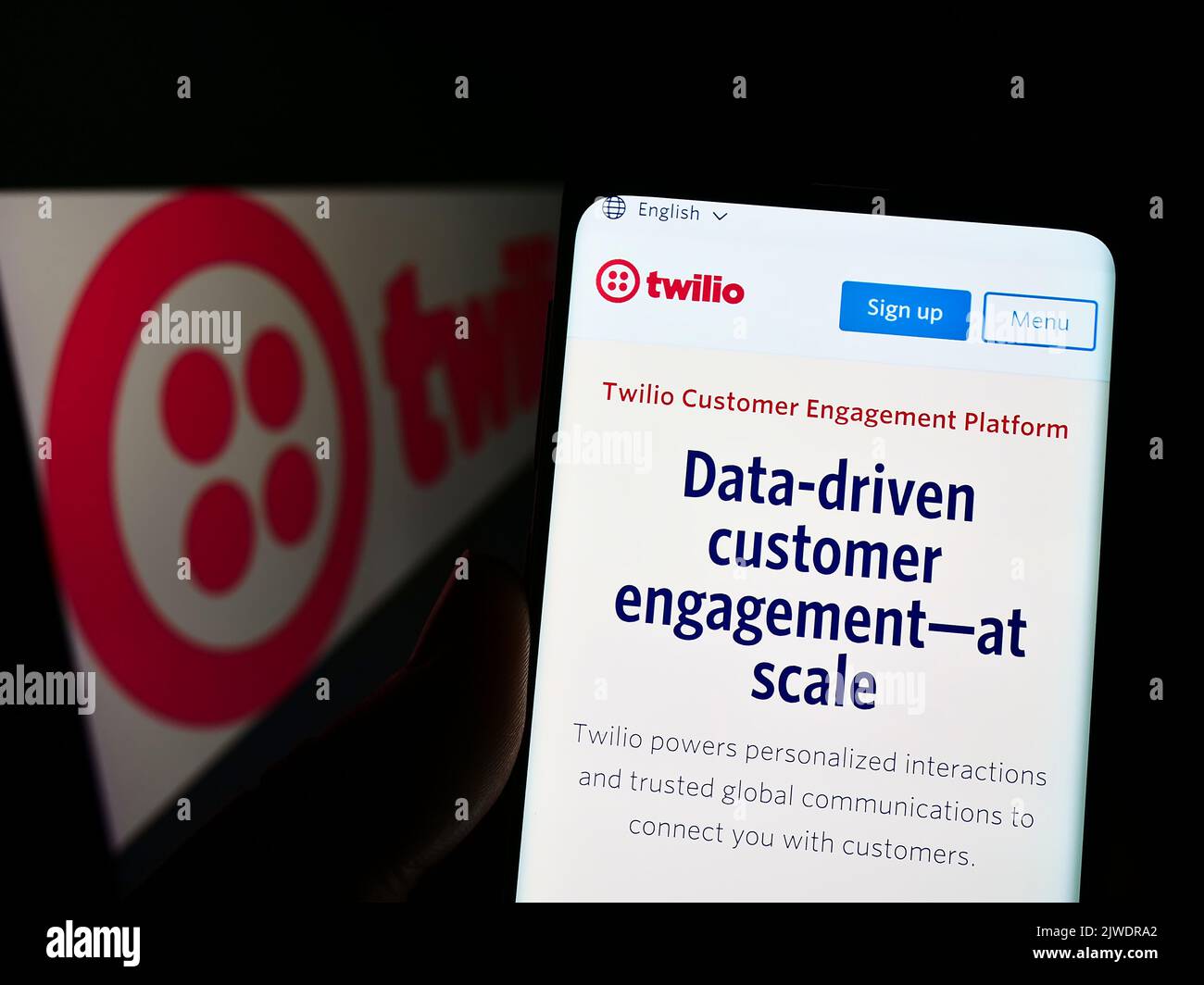 Person holding cellphone with website of US communications platform company Twilio Inc. on screen with logo. Focus on center of phone display. Stock Photo