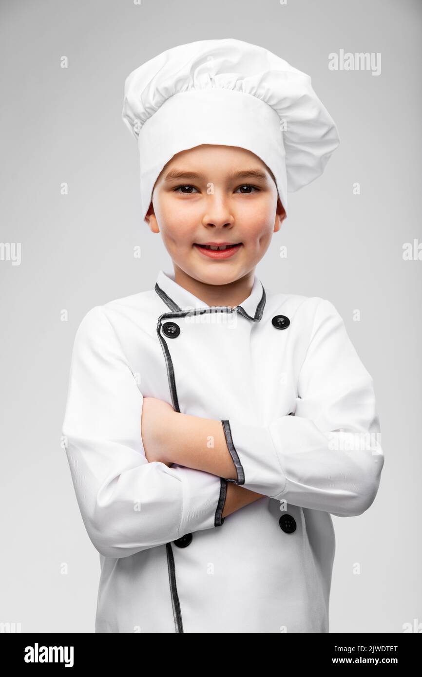 smiling little boy in chef's toque and jacket Stock Photo