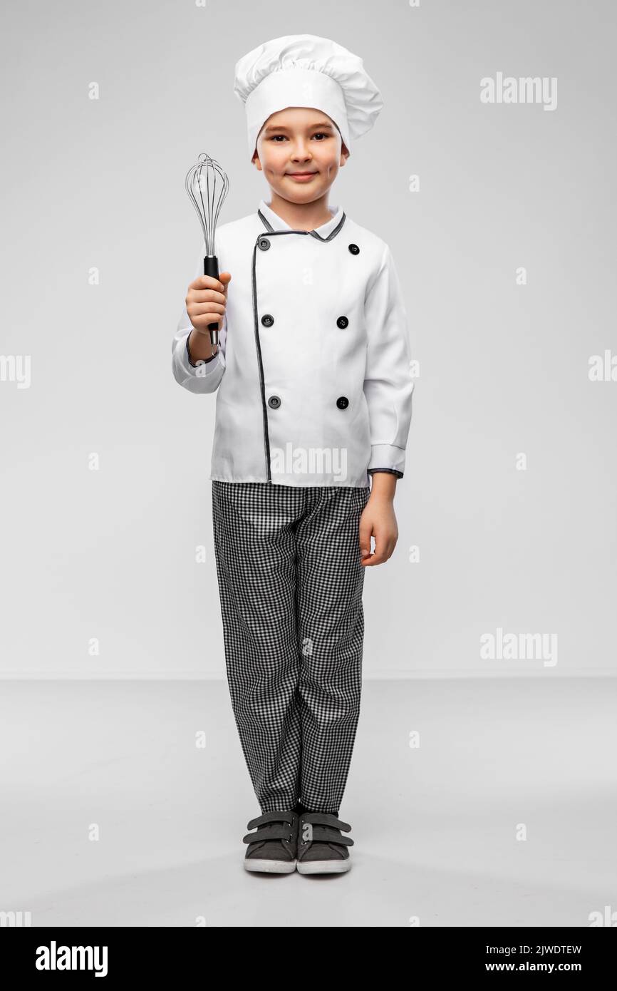 smiling little boy in chef's toque with whisk Stock Photo