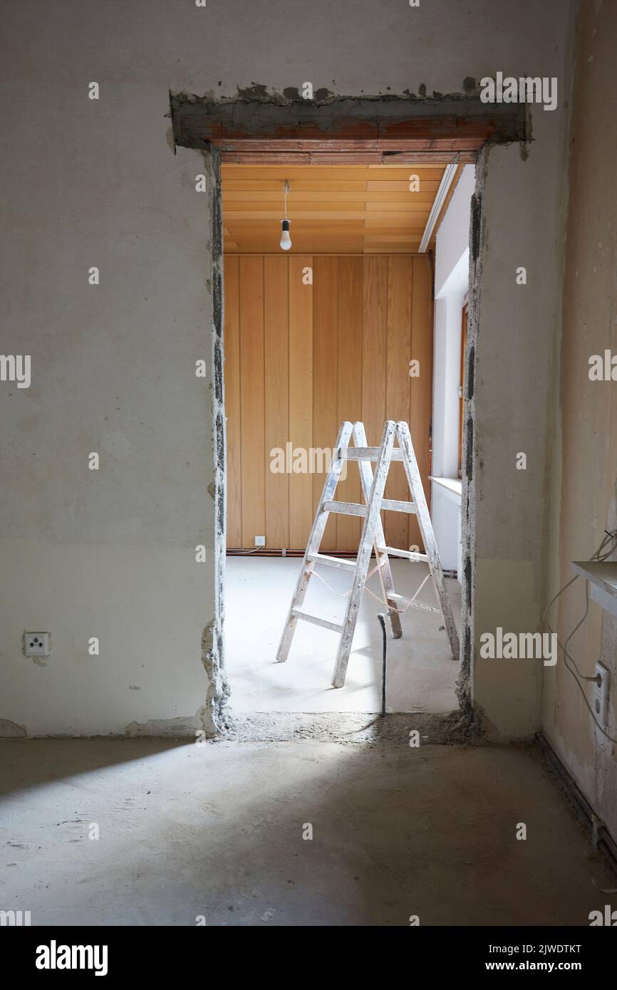 Wall breakthrough for a room door, behind it a painter's ladder Stock Photo