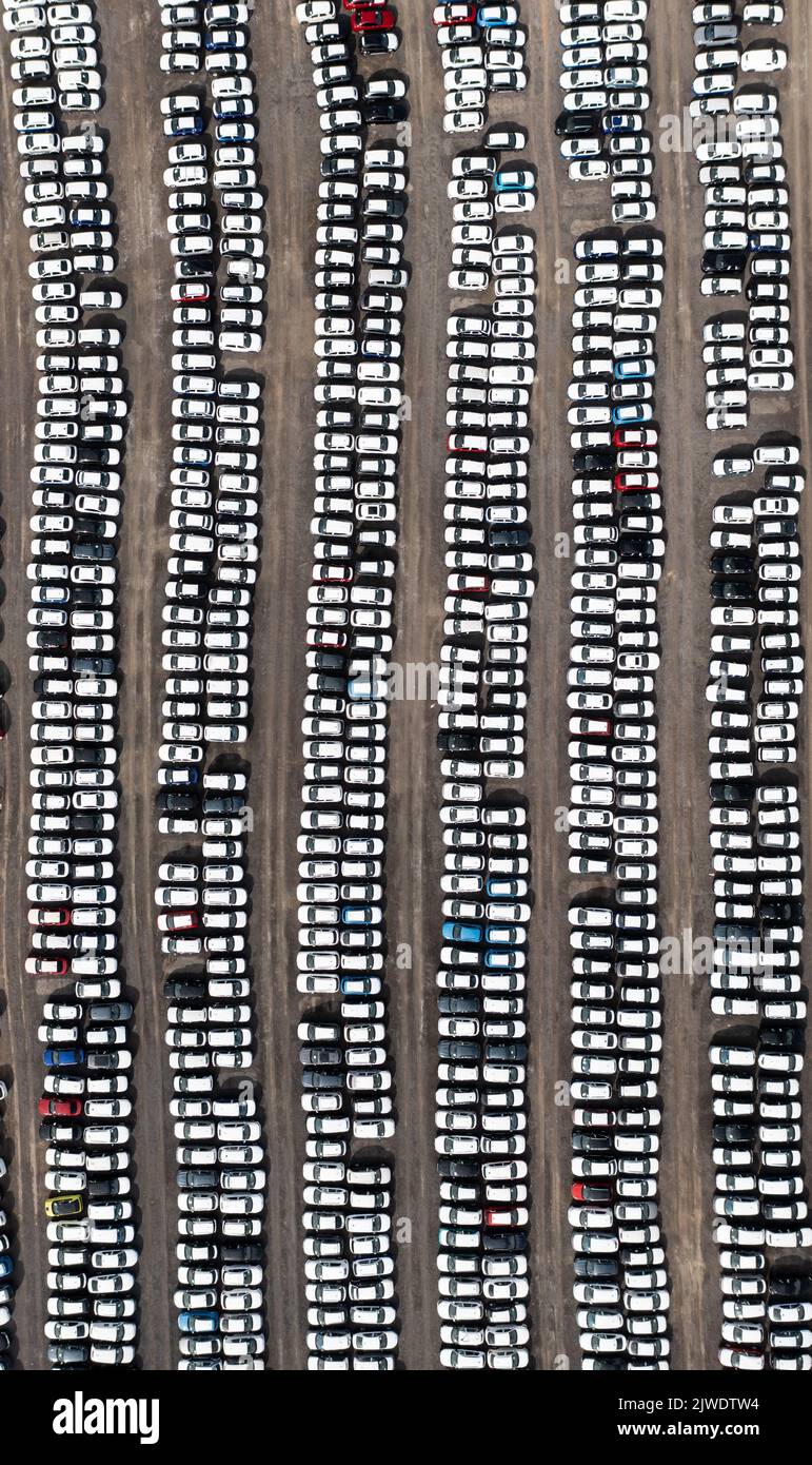 An aerial view of rows of newly built cars and vehicles ready for export and import and delivery to sales dealerships on a port or terminal dock Stock Photo