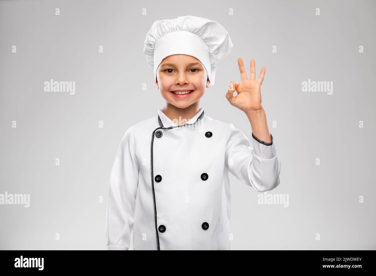 little boy in chef's toque showing ok gesture Stock Photo