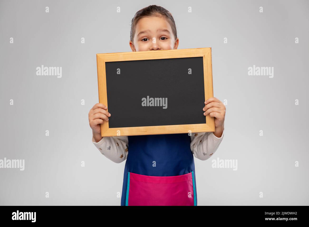 little girl in apron holding chalkboard Stock Photo