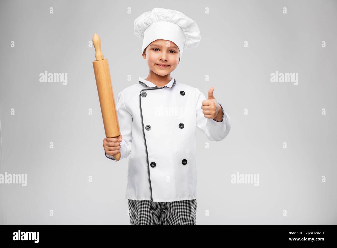 chef girl with rolling pin showing thumbs up Stock Photo