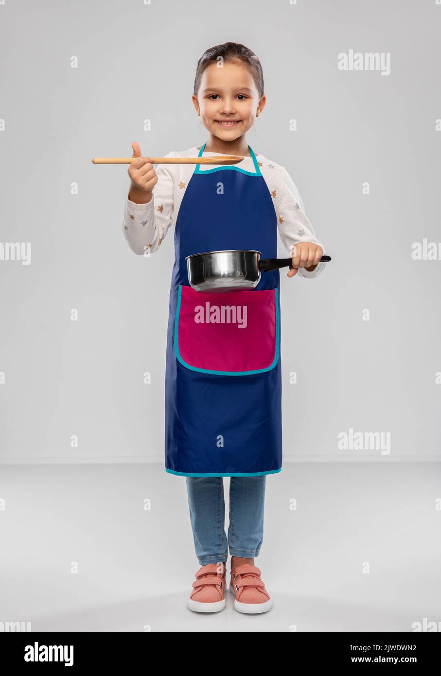 little girl in apron with saucepan cooking food Stock Photo