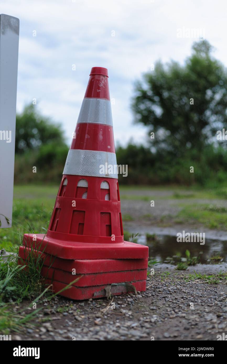 A vertical shot of several red and white traffic cones in a garden in a