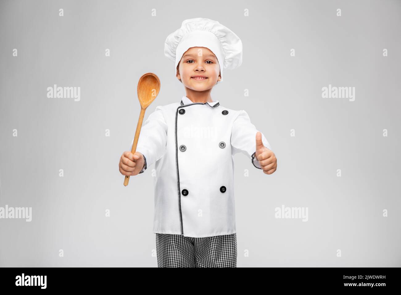 girl in chef's toque with spoon showing thumbs up Stock Photo