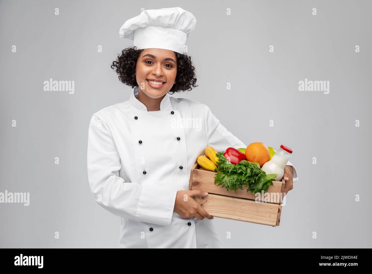 happy smiling female chef with food in wooden box Stock Photo