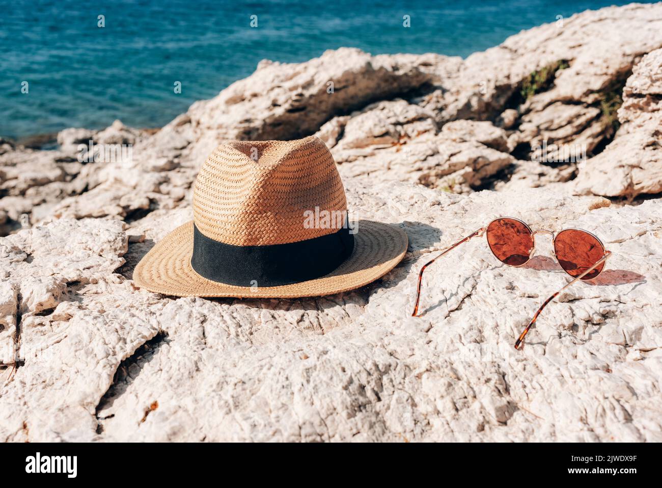 Straw hat and sunglasses on the rocky shore. Summer vacation concept ...