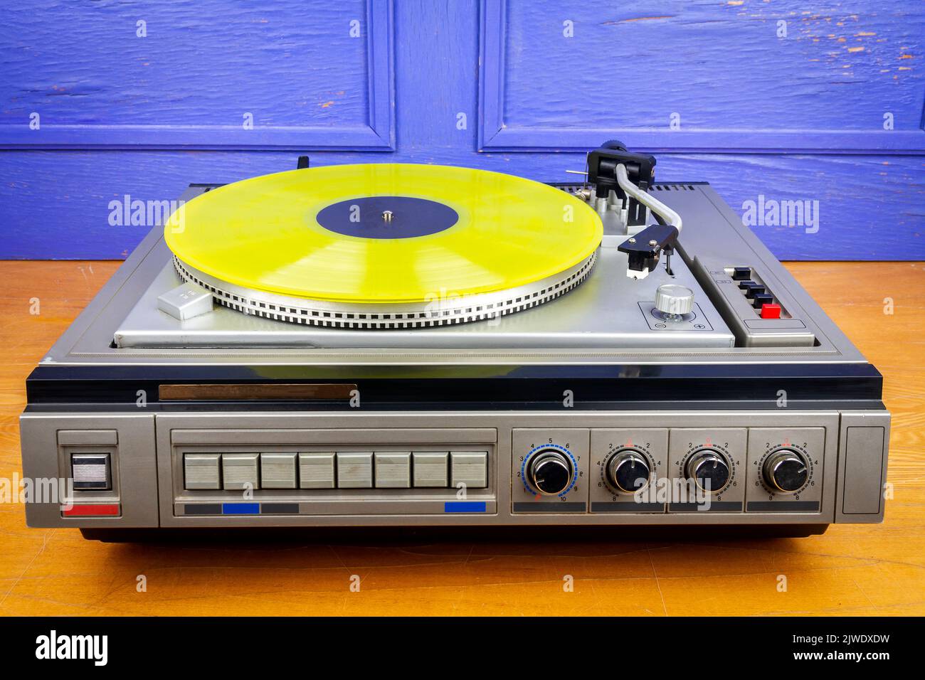 Vintage turntable vinyl record player with yellow vinyl on a table ...