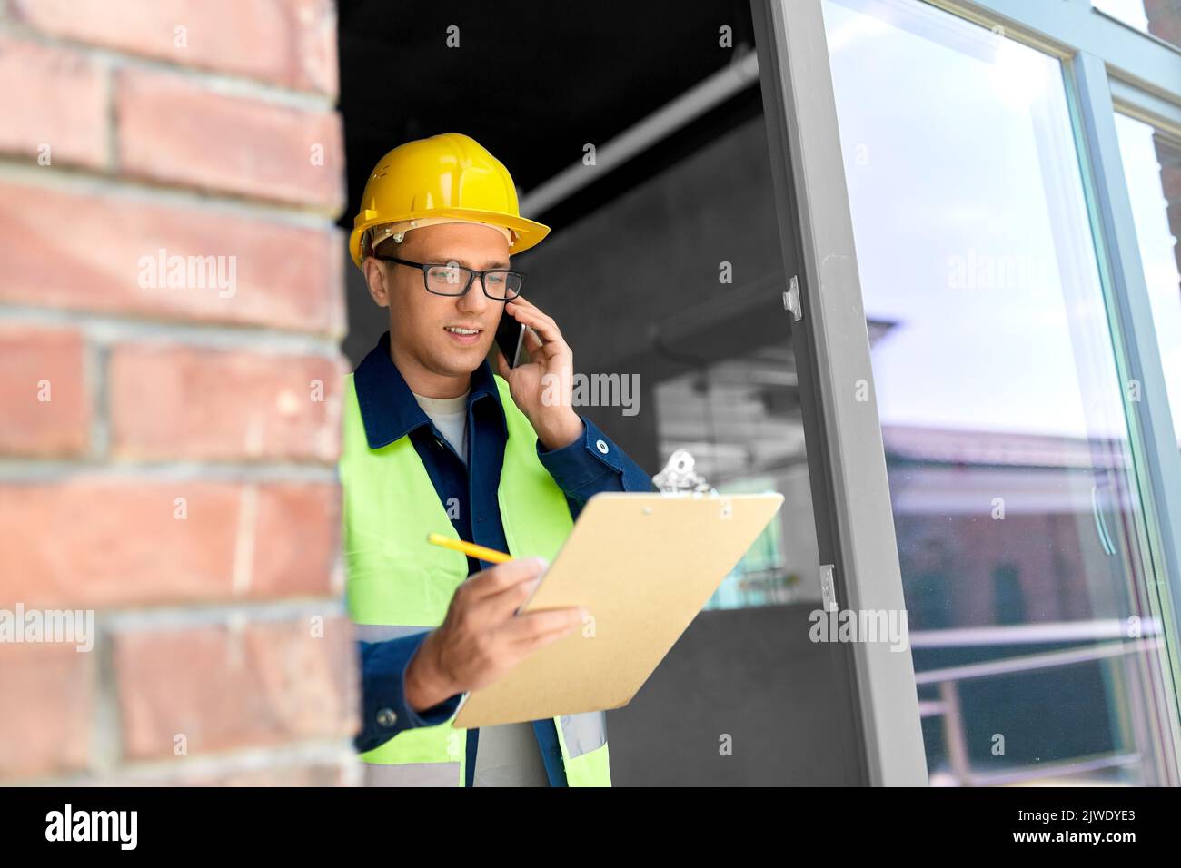 builder with clipboard and calling on smartphone Stock Photo