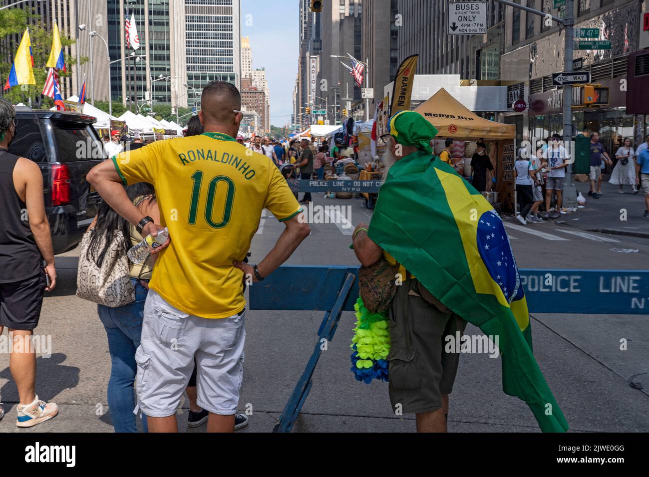 People wearing Brazilian shirts and flags enjoy a street fair on Sixth