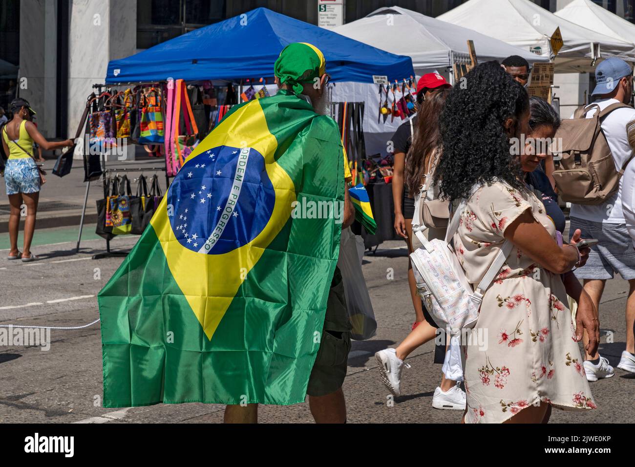 People wearing Brazilian shirts and flags enjoy a street fair on Sixth