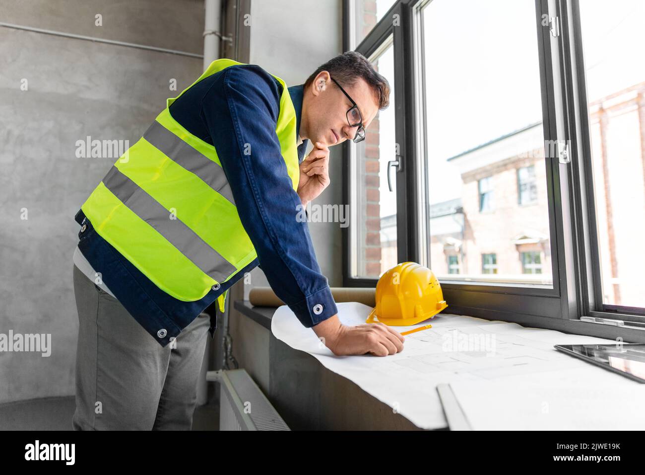 male architect with blueprint working at office Stock Photo