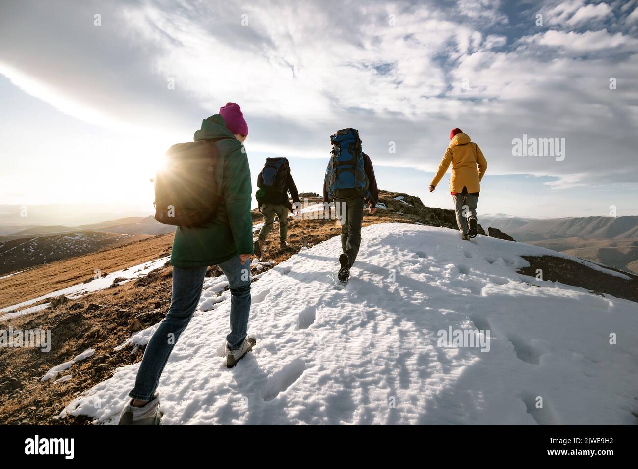 Group of young tourists hikers walks on mountain top with backpacks. Active life concept Stock Photo