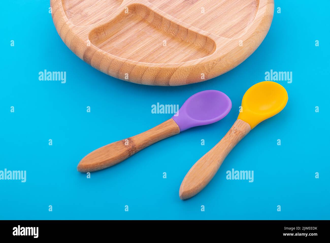 Wooden bowl. Bamboo plate with spoon isolated on blue background Stock Photo