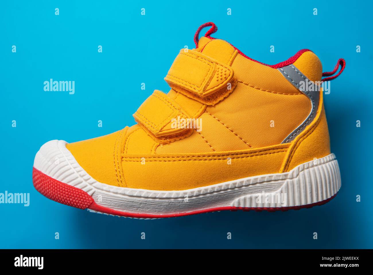 Yellow baby shoes. Kids sport sneakers isolated on blue background Stock Photo