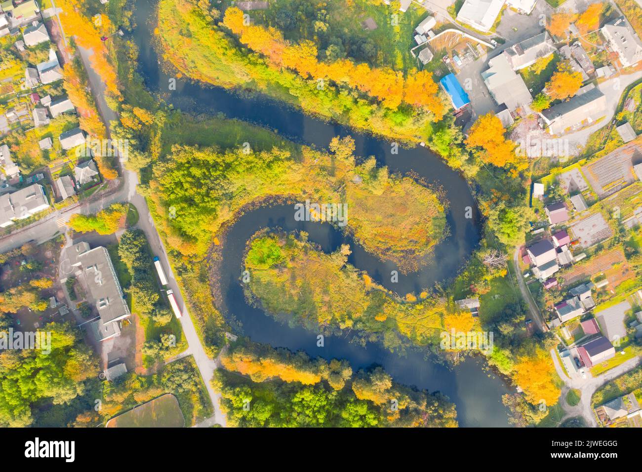 Aerial view of a beautiful meandering river. Aerial view. River bends, trees in the middle of a small town. Colorful aerial landscape of the river coa Stock Photo