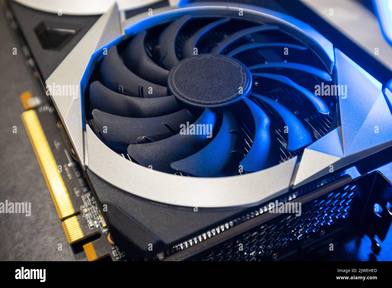 Gpu graphics card top view. Cooler fan close-up in bright blue light, PC hardware details. Components from computer cooling system with selective focu Stock Photo