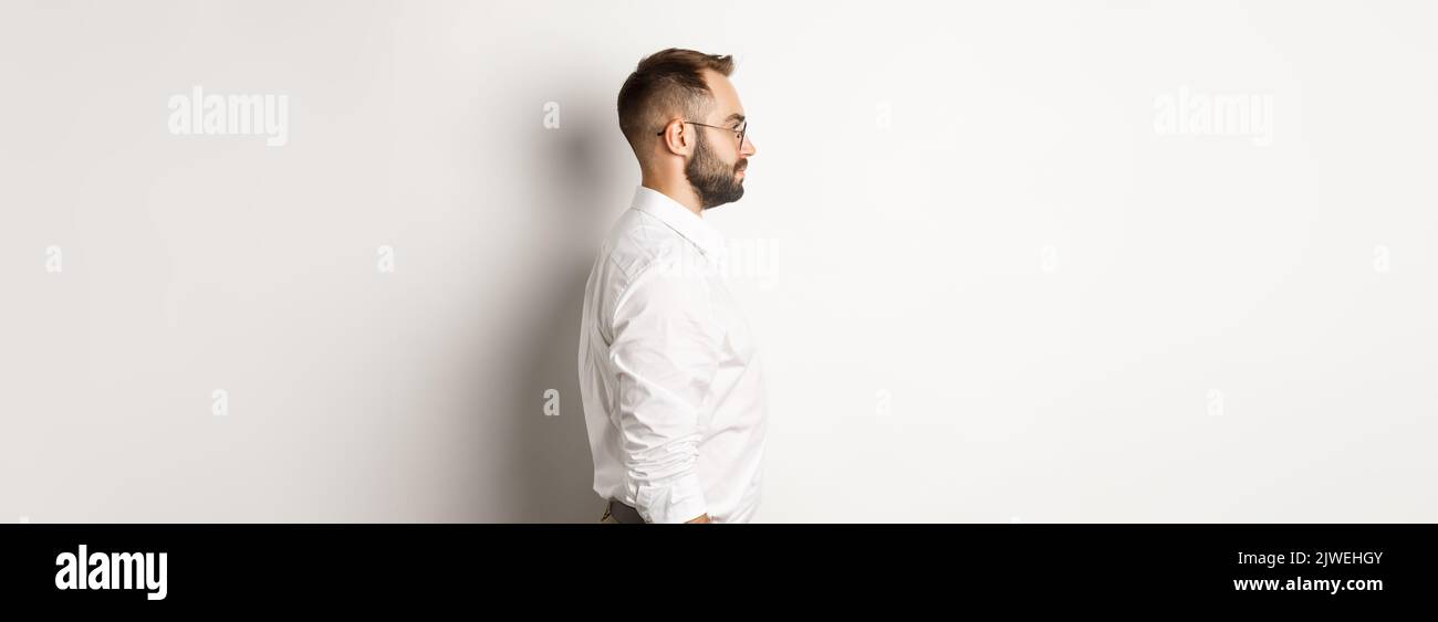 Left Standing Profile of young businessman in white collar shirt and beige pants ...