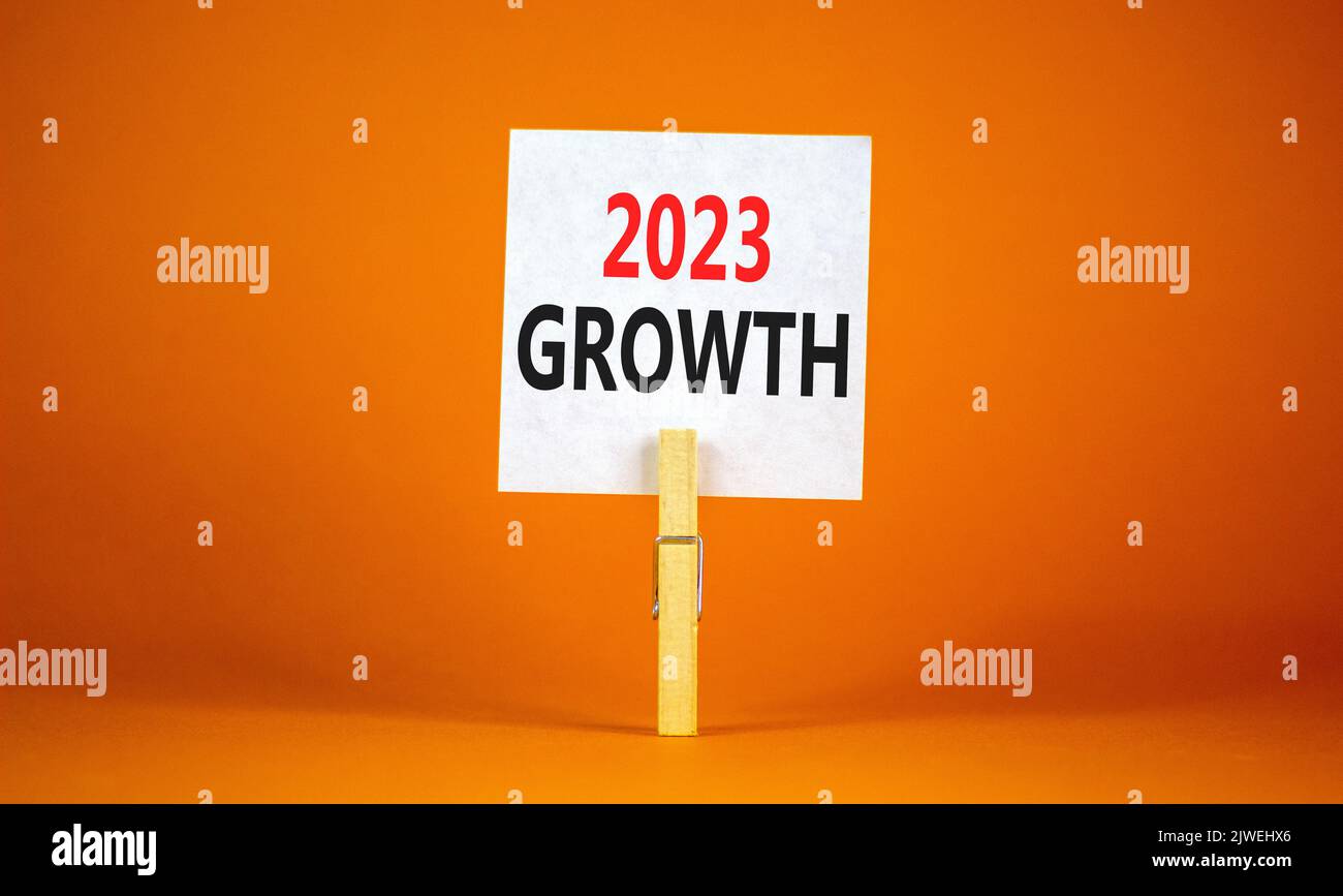 2023 Growth symbol. White paper with words 2023 Growth, clip on wooden clothespin. Beautiful orange table orange background. Business and 2023 growth Stock Photo