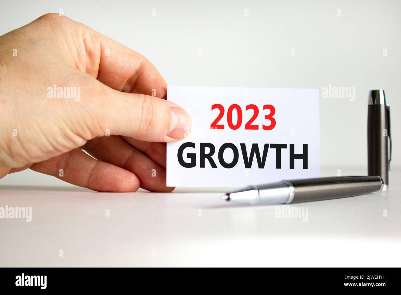 2023 Growth symbol. White paper with words 2023 Growth. Businessman hand. Metallic pen. Beautiful white table white background. Business and 2023 grow Stock Photo