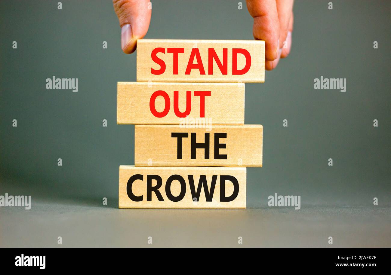 Stand out the crowd symbol. Concept words Stand out the crowd on wooden blocks on beautiful grey