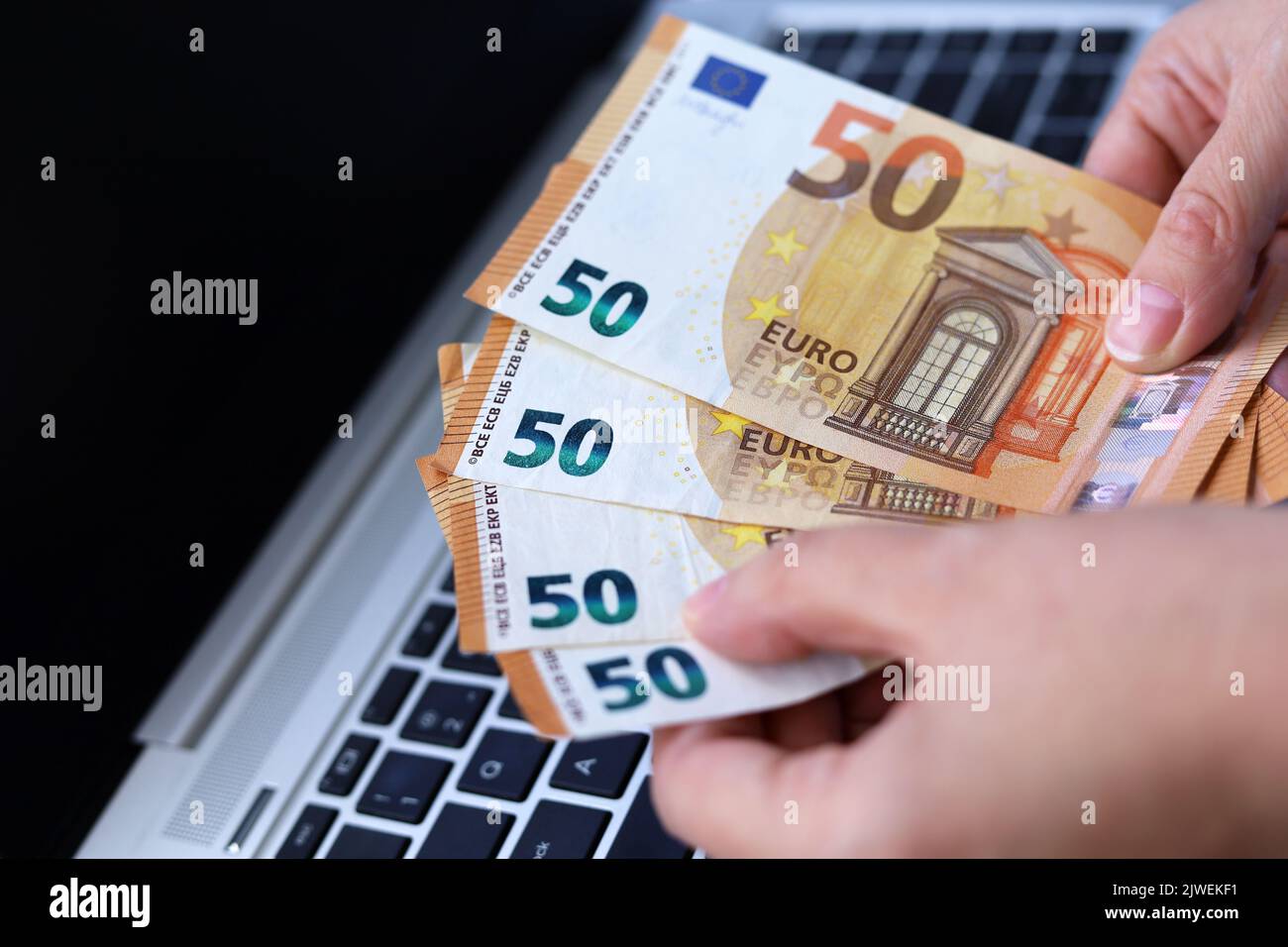 Euro banknotes in female hands on laptop background. Woman counting money, concept of wages or bonus Stock Photo