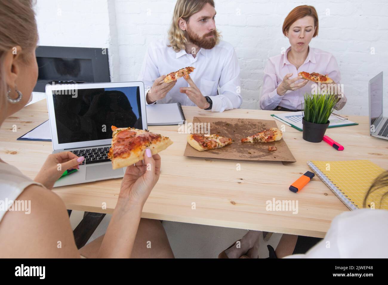 Diverse business team people workers eating pizza together at workplace, friendly multi-ethnic colleagues group talking enjoying having fun and corpor Stock Photo