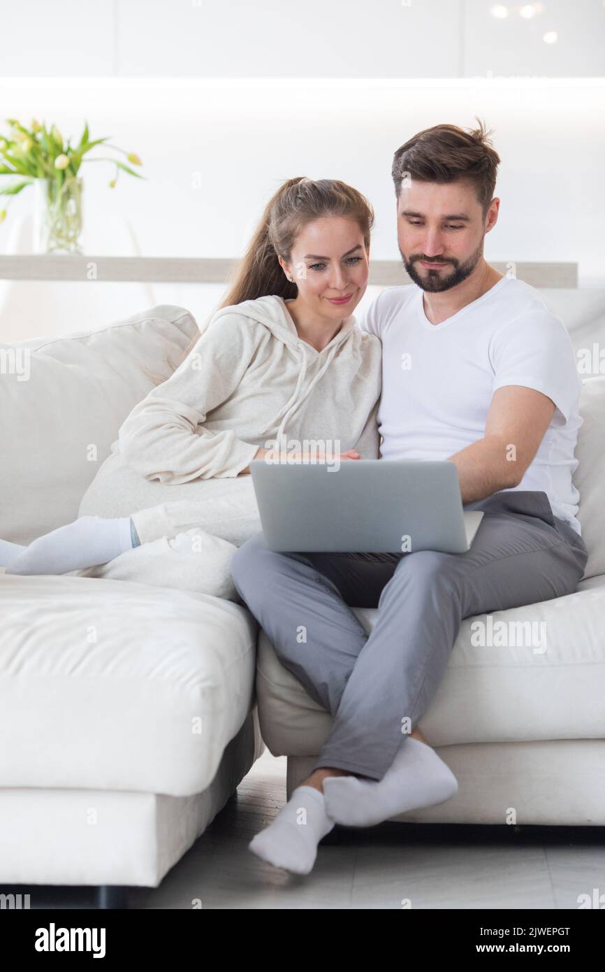 Happy married couple spending free leisure weekend holiday time with laptop indoors. Stock Photo